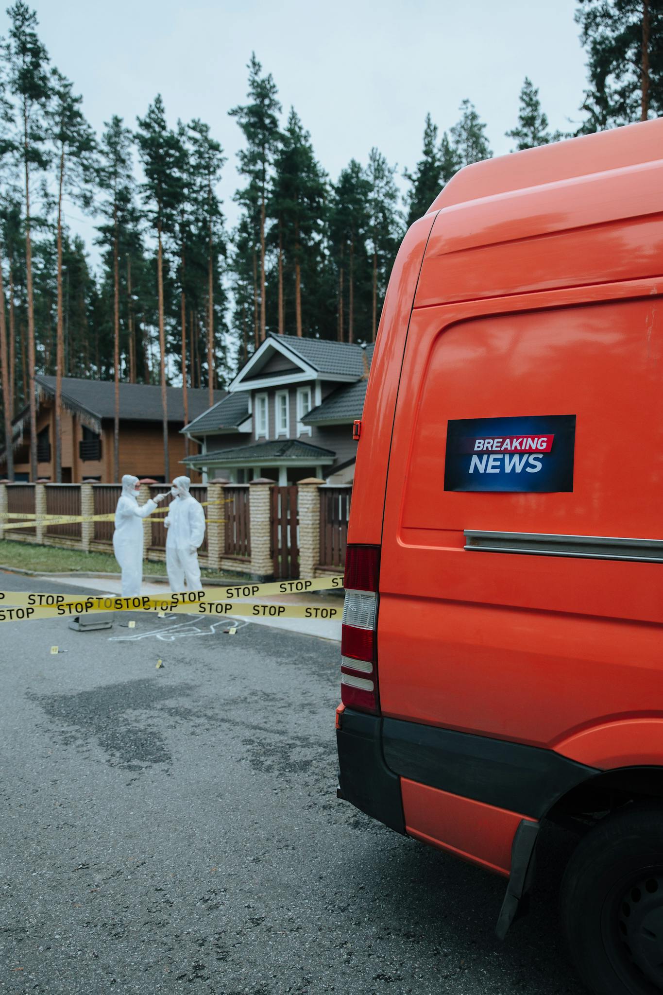 Forensic team investigates a crime scene in a residential neighborhood with a media van parked nearby.